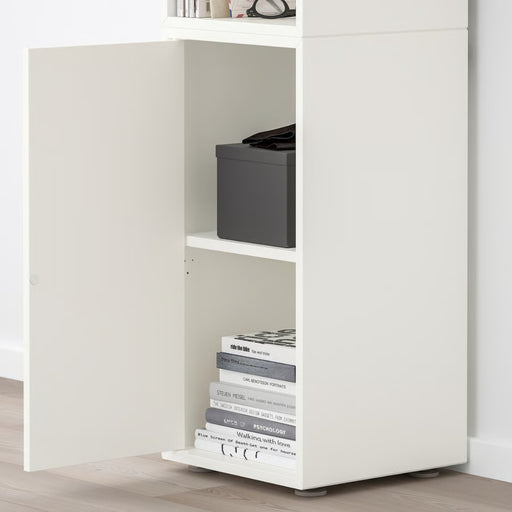 White storage cabinet with shelves containing books and a black box.