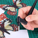 Hand using a craft knife on a cutting mat with butterfly templates