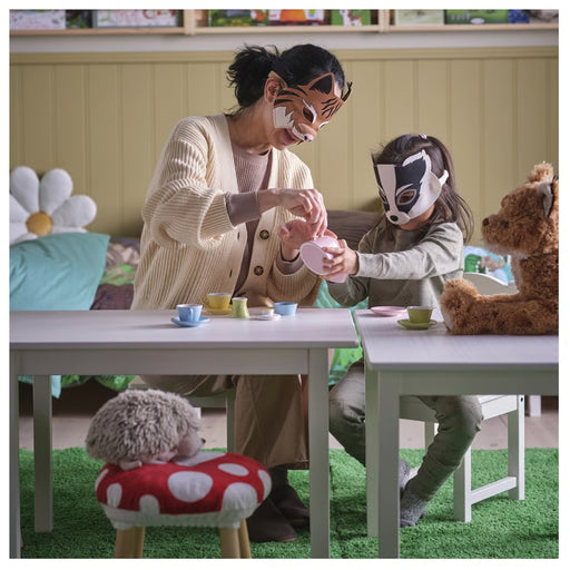 Woman and child wearing animal masks at a table with toys and cups.