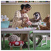 Woman and child wearing animal masks at a table with toys and cups.