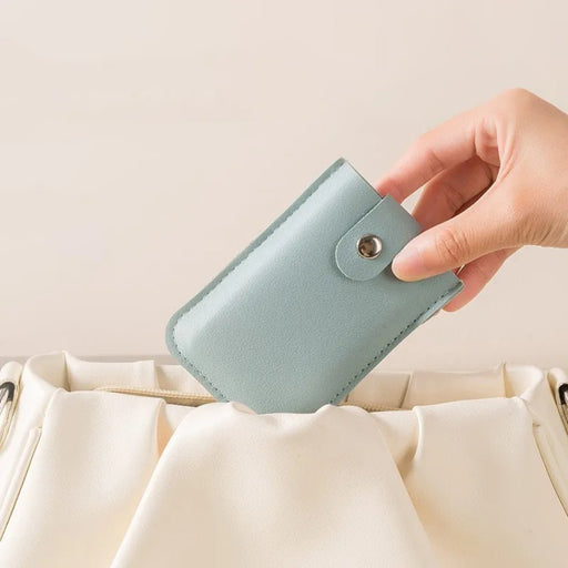 Hand holding a light blue wallet against a beige background