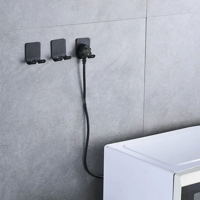 Wall-mounted black hooks organizing power cord and plug above white appliance