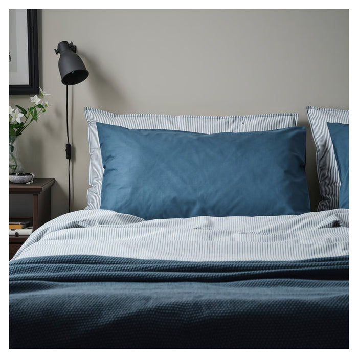 Bed with blue bedding and pillows in a bedroom setting.