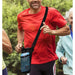Man in red shirt running outdoors with a blue water bottle holder on his shoulder