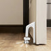 Anti-theft door stopper—shown wedged under the door with metallic base touching the floor and directional arrows indicating locking motion; enhances entry protection – 1600003772922 13245865.