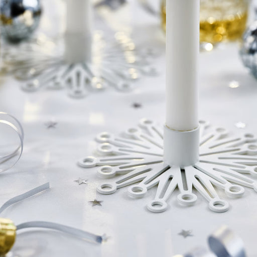 FRÖJDA candlesticks styled on a festive table with metallic confetti, ribbon curls, and silver-gold ornaments