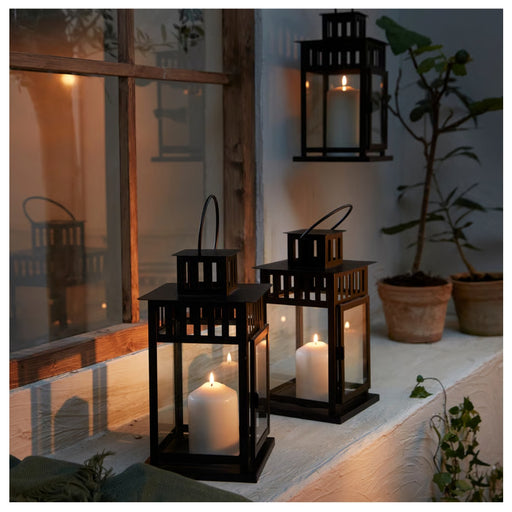 Black lanterns with candles on a windowsill at night