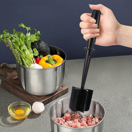 Hand using a meat grinder with a bowl of vegetables and a small bowl of eggs in the background.