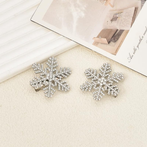 Crystal snowflake hair clips – pair of rhinestone accessories on textured surface with decorative cards