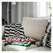 Black and white zigzag blanket with colorful edges on a gray sofa.