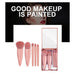 Set of pink makeup brushes with a mirror in a box, featuring the text 'Good Makeup is Painted' on a black background.