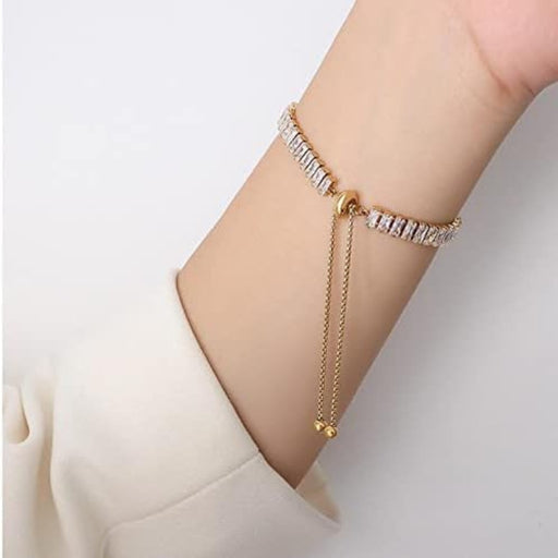 Gold rhinestone bracelet – worn on wrist with dangling chain ends and elegant white sleeve background