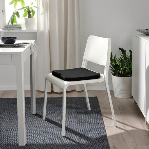  IKEA STAGGSTARR pad placed on white dining chair beside table with black bowl and striped napkin in modern setup