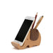 Wooden elephant phone stand holding a smartphone and two pens on a white background
