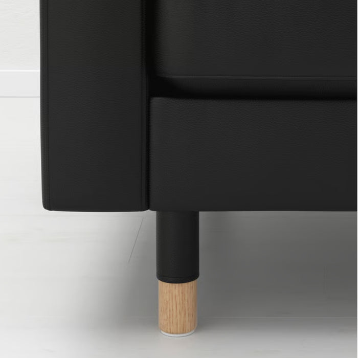 Close-up of an IKEA LANDSKRONA Leg, wood, 15 cm 5 7/8 inches, attached to a black upholstered furniture piece—showcasing the sturdy wooden base and modern design for enhanced stability and style -50292398.