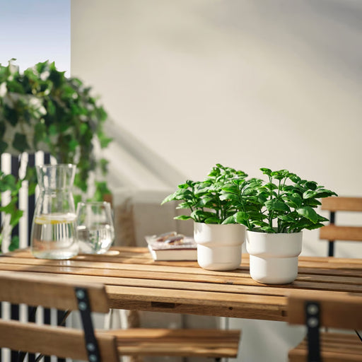 Small FEJKA artificial basil plant used as a decorative accent on an outdoor patio table.