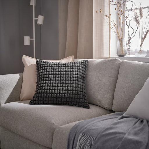 SVARTPOPPEL cushion styled on light gray sofa with beige throw pillow and fringed blanket, paired with neutral curtains and decorative vases
