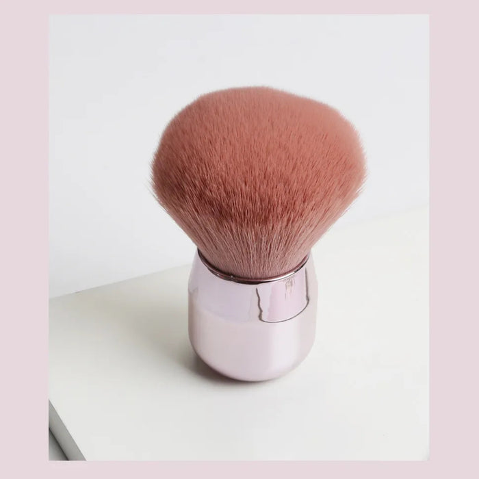 Close-up of pink-bristled makeup brush with glossy compact handle on white surface