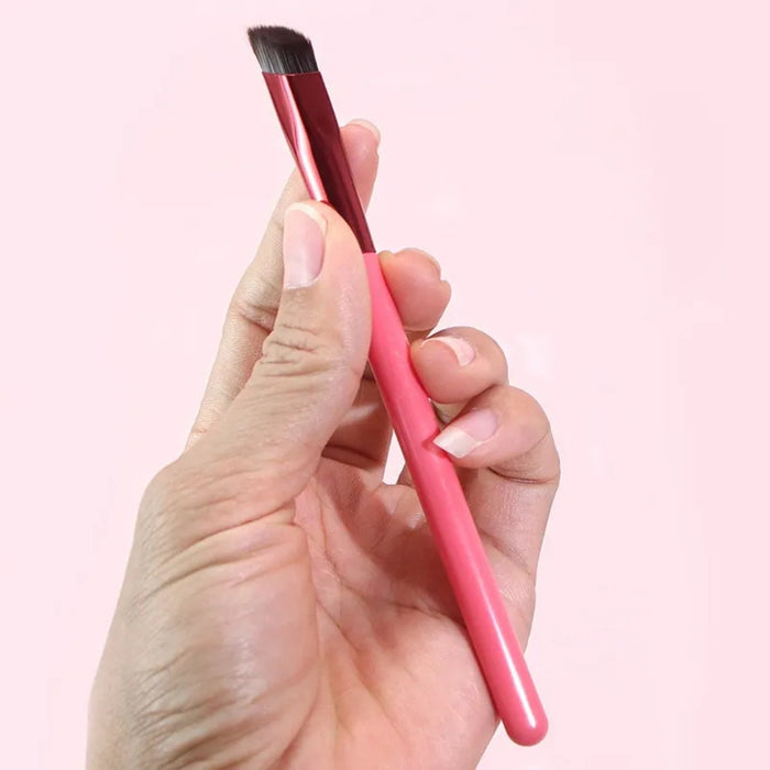 Hand holding red angled eyebrow brush with dark bristles – designed for precise brow filling and hairline detailing – 1598453751840 14041847