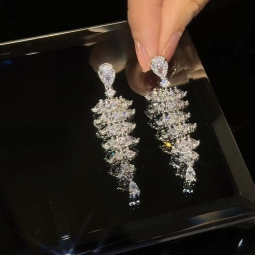 Hands holding a pair of chandelier-style earrings with marquise and pear-cut stones in a fan-like design – 1600002193457 14066565