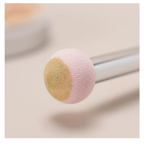 Makeup brush with pink and beige bristle head on a light background