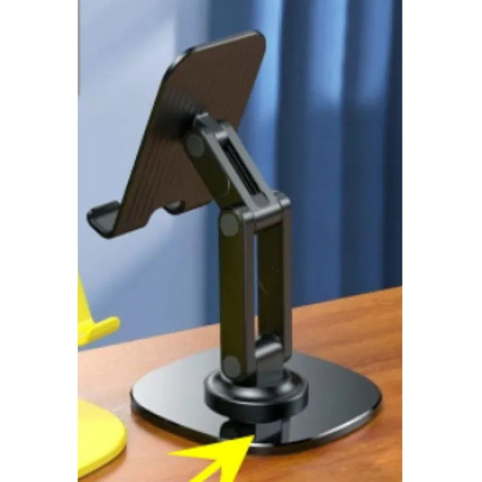 Black adjustable phone/tablet stand with dual hinges, circular base, and highlighted yellow arrow pointing to the folding mechanism—shown on wooden surface with blue curtain backdrop – 1600006845076 13109076.