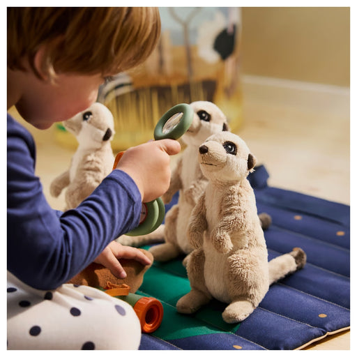 Child playing with plush meerkats on a blue mat