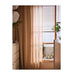 Sheer beige curtain in front of a window with blinds, interior decor.