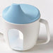 White mug with a blue lid on a light gray background