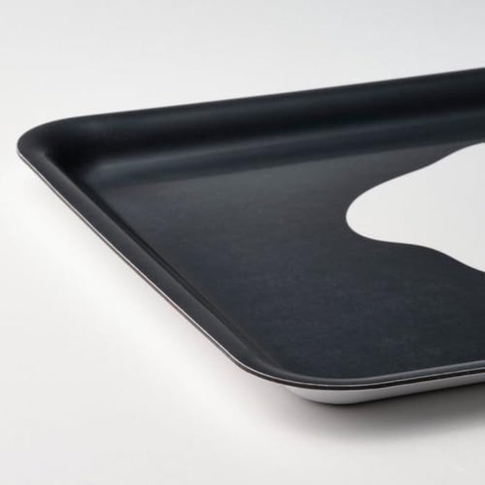 Close-up of the IKEA KEJSARFISK tray in patterned multicolour—features a bold black surface with a central fried egg motif, where the white and yellow design pops vividly against the dark background. The tray’s rounded corners and raised edges are visible, emphasizing its smooth finish and practical grip. Ideal for serving snacks or drinks with a playful twist – 50607690.