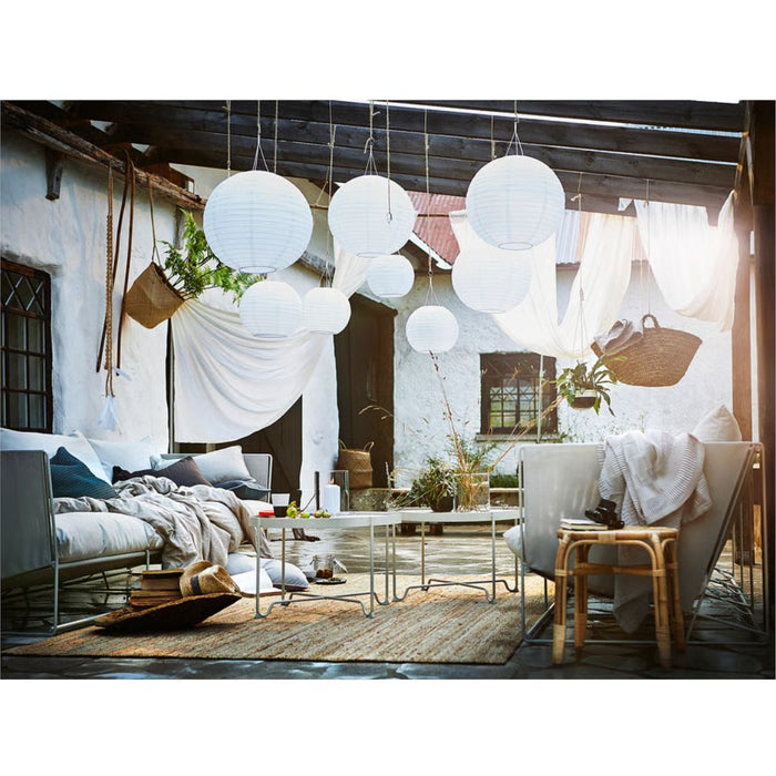 Modern outdoor living space with white pendant lights, comfortable seating, and decorative elements.