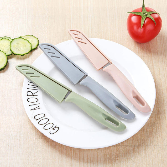 Three colorful Peeling Fruit Knife knives on a white plate with vegetables on a wooden surface