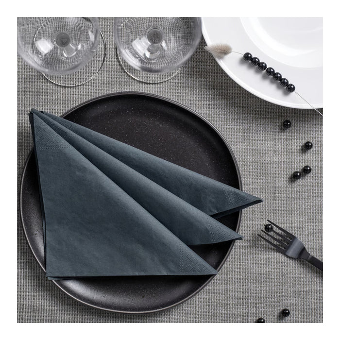 Dark gray napkin folded on a black plate with a gray placemat, glasses, and blackberries.