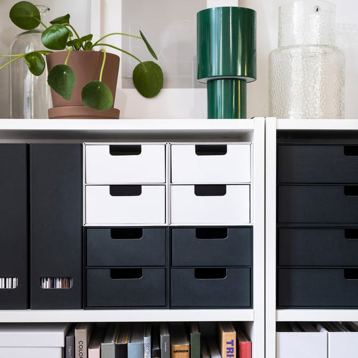 Storage drawers in black and white on a shelf with decorative items.