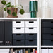 Storage drawers in black and white on a shelf with decorative items.