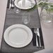 Table setting with white plates, silverware, and a geometric black and white placemat.