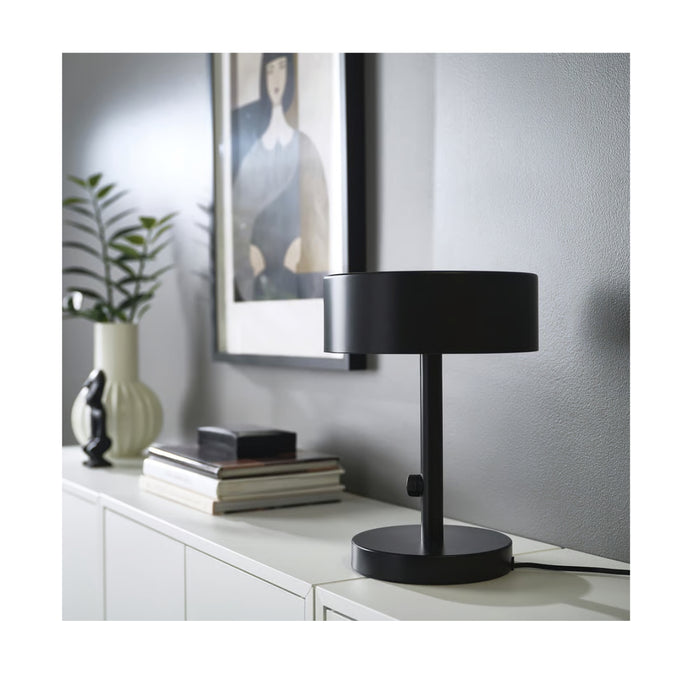 Black table lamp on a white surface with a neutral background