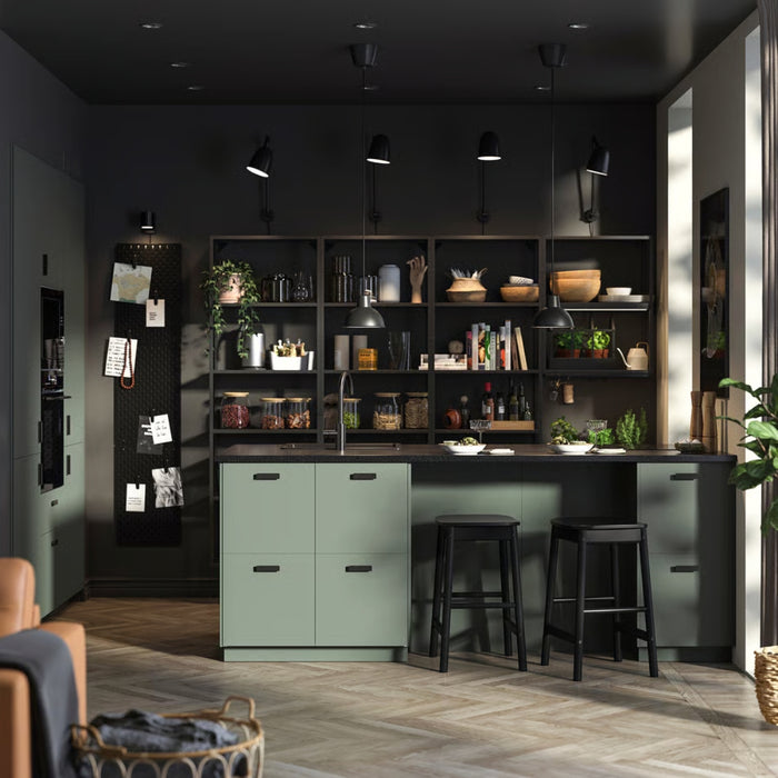 Modern kitchen with dark walls, green island, and black bar stools.