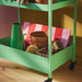Folded IKEA DOFTRIPS gardening mat stored neatly on a green rolling utility cart alongside flower pots.