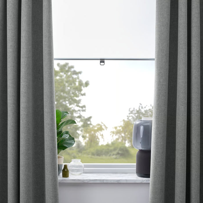 Gray curtains partially drawn to reveal a window with a view of greenery outside.