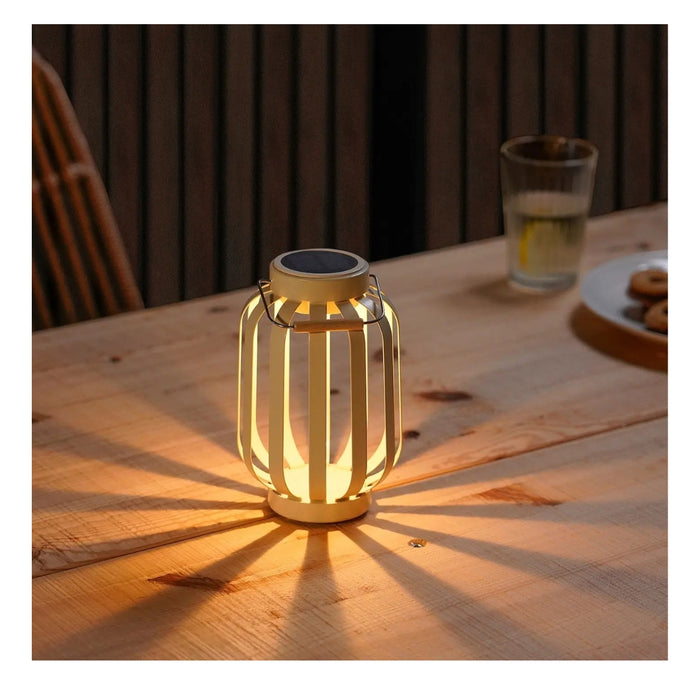 Solar-powered lantern on a wooden table with a glass of water and cookies in the background.