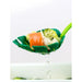 Green leaf-shaped spoon with food on a white background