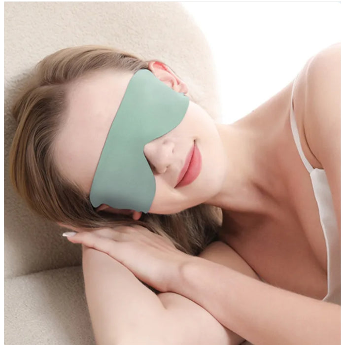 Woman wearing a green sleep mask on a beige pillow