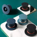 Collection of top hat-shaped silicone accessories in black, blue, and navy with red/pink bands – shown supporting smartphone on glossy surface – 1600002389866 13964736