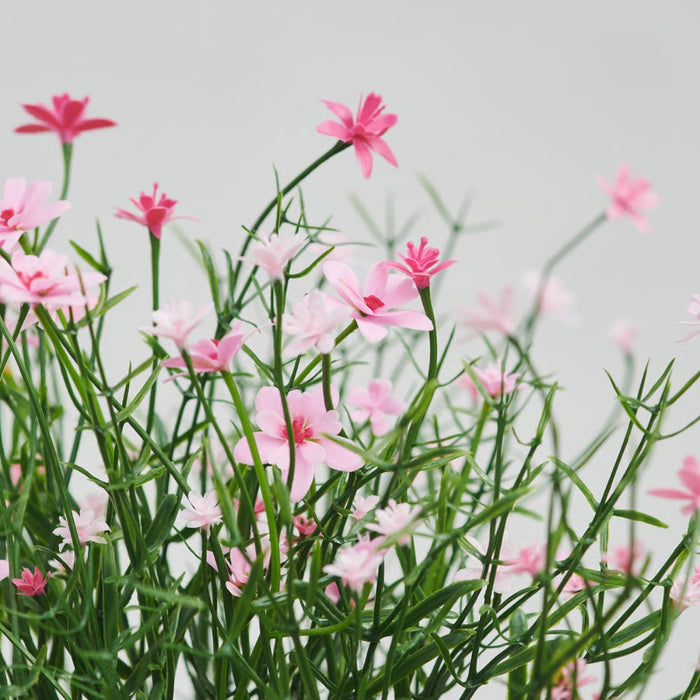 Close-up of IKEA FEJKA artificial baby’s breath pink flowers against light background