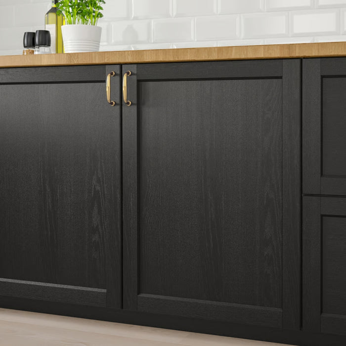 Black kitchen cabinets with gold handles on a wooden countertop.