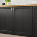 Black kitchen cabinets with gold handles on a wooden countertop.