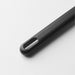 A close-up of a matte black kitchen utensil handle with an oval hole for hanging, lying on a light gray surface.