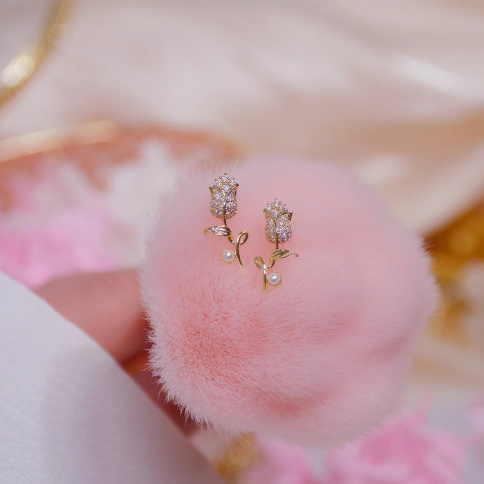 Gold earrings with pearls on a pink fluffy surface