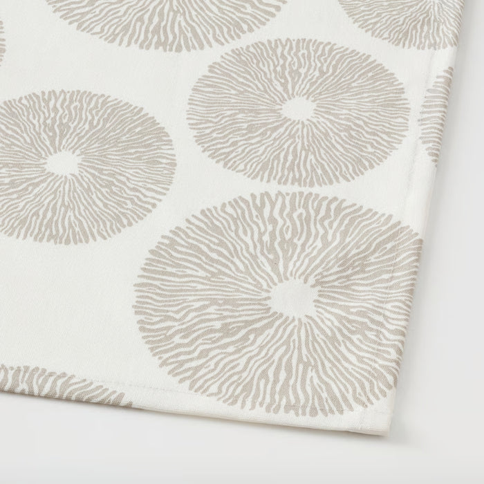 Close-up of the IKEA HÅRSTARR tablecloth showcasing its beige fabric with a repeating circular pattern resembling sunbursts or stylized floral rings. The design features fine radial lines that give the tablecloth a textured and elegant appearance. The neutral tones and delicate detailing lend themselves well to both contemporary and traditional dining setups—ideal for elevating everyday meals or special gatherings -30519699.